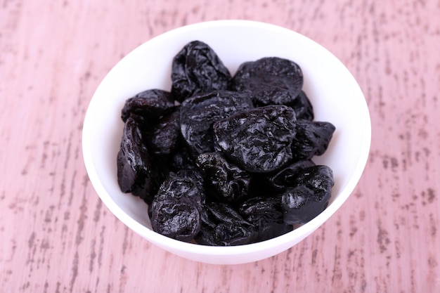 Tigela com pilha de ameixas na cor de fundo de madeira