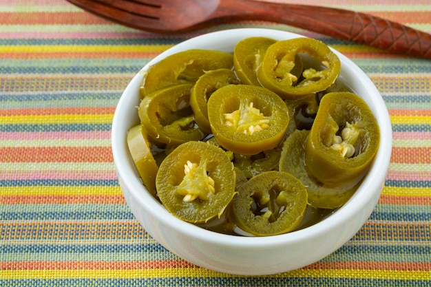 Tigela com pimenta jalapeno verde em conserva fatiada fechada