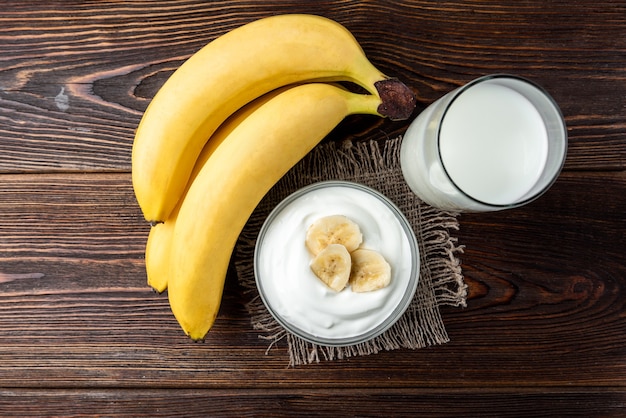 Foto tigela com rodelas de banana e iogurte e copo de leite