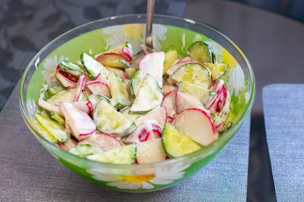 Tigela com salada primaveril de rabanete e pepino temperada com molho