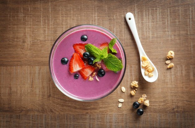 Tigela com smoothie de açaí e frutas em fundo de madeira