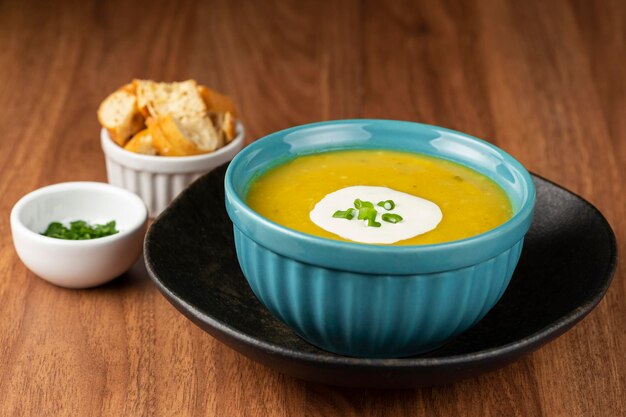 Tigela com sopa de abóbora em cima da mesa.