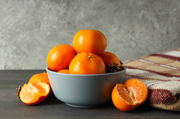 Tigela com tangerinas e xadrez na mesa de madeira escura