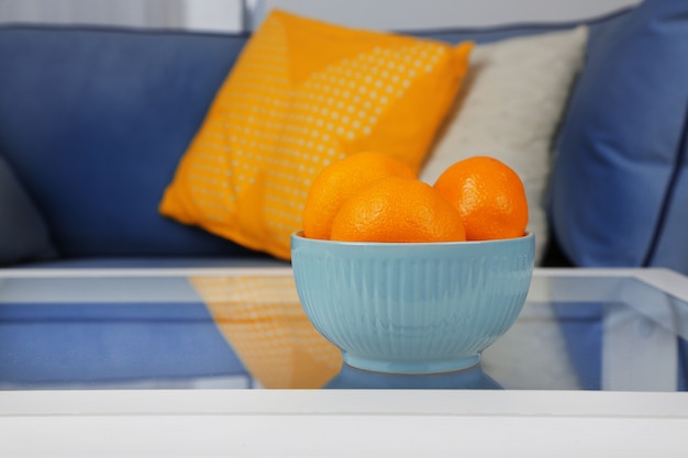 Tigela com tangerinas frescas na mesa da sala de estar, close-up