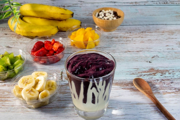 Tigela de açaí em mesa de madeira frutas frescas no fundo