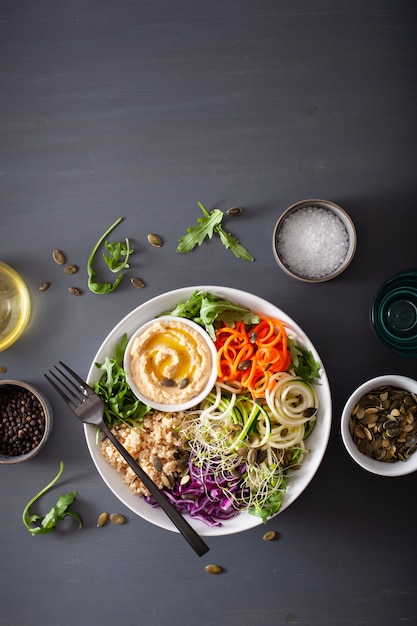 Tigela de almoço de cuscuz vegetariano com cenoura em espiral e abobrinha, hummus e repolho roxo