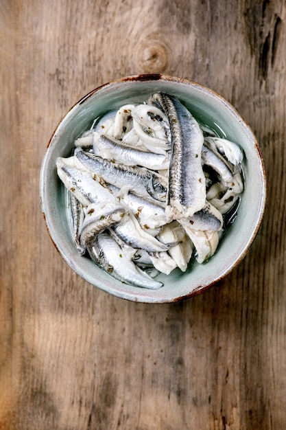 Tigela de anchovas em conserva ou filé de sardinha em óleo com ervas para tapas ou antepastos sobre madeira velha