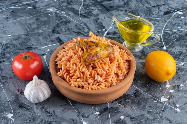 Tigela de barro com deliciosa massa fusilli com asa frita na superfície de mármore.