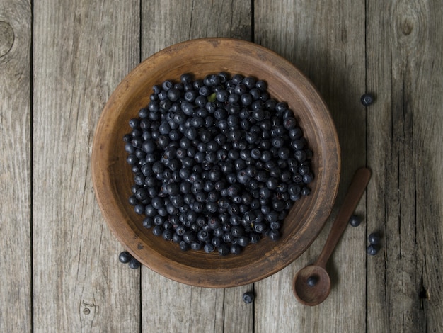 Tigela de barro com mirtilos em uma velha mesa de madeira. Bagas recém colhidas. Superfood antioxidante do mirtilo, conceito para comer saudável.