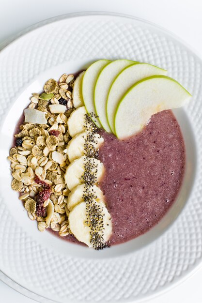 Tigela de batido com banana, maçã, sementes de Chia, granola e iogurte.