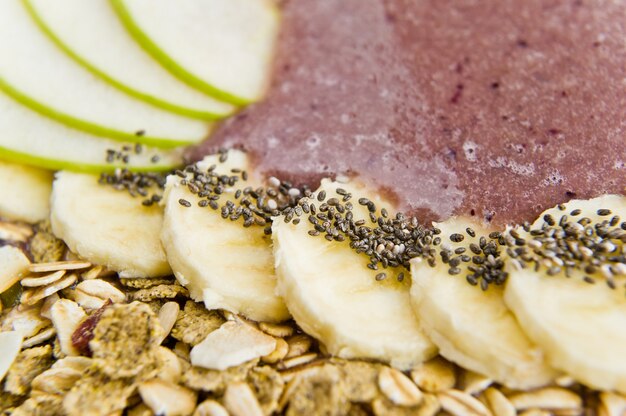 Tigela de batido com banana, maçã, sementes de Chia, granola e iogurte.