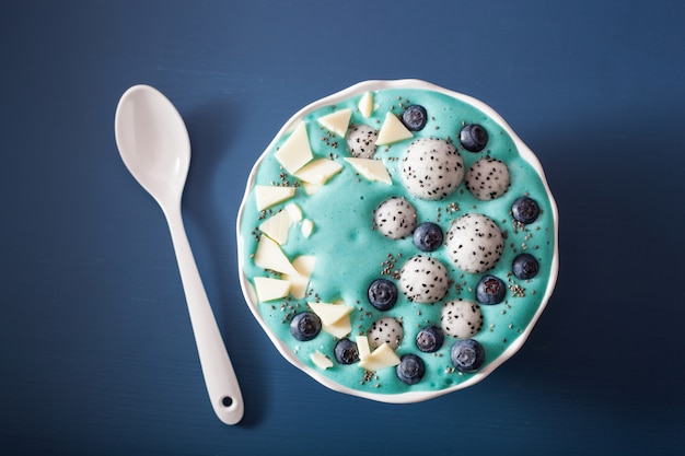 Tigela de batido de spirulina azul saudável com mirtilo, chocolate branco, fruta do dragão, semente de chia