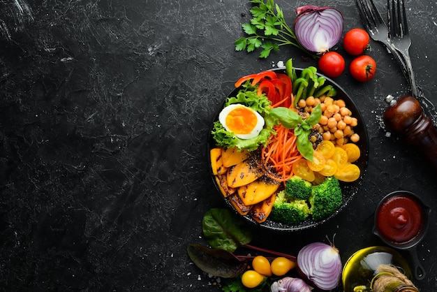 Tigela de Buda abóbora brócolis ovo tomate cenoura páprica em um prato preto em um fundo preto Vista superior Espaço livre para o seu texto