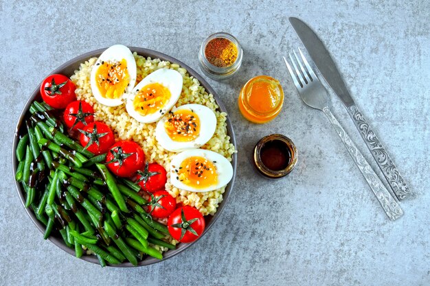 Tigela de Buda com bulgur, feijão verde, tomate cereja e metades de ovo cozido. Comida saudável em uma tigela. O conceito de nutrição dietética.