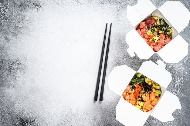 Foto tigela de buda em caixa de papel com legumes, salmão e atum. comida de rua para levar, levar embora.