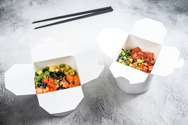 Foto tigela de buda em caixa de papel com legumes, salmão e atum. comida de rua para levar, levar embora.