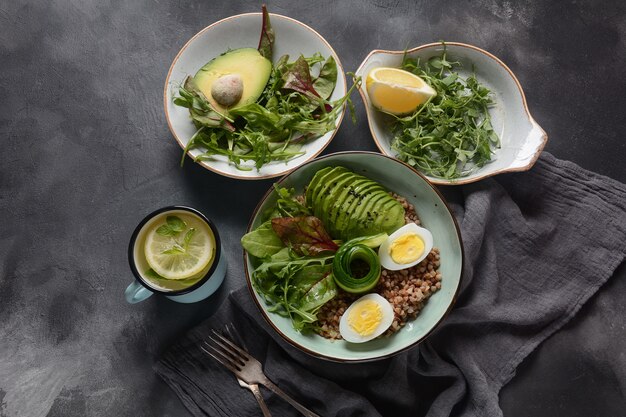 Foto tigela de buda vegan com trigo sarraceno, abacate, ovos cozidos, pepino, folhas de beterraba rúcula. dieta, desintoxicação, conceito de comida saudável