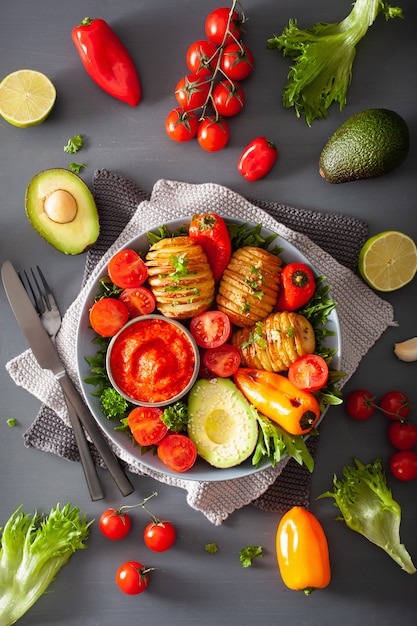 Tigela de buda vegan. tigela de almoço saudável com batata hasselback, abacate, tomate, pimentão e molho de pimenta