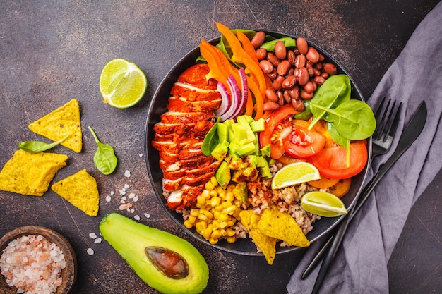 Tigela de burrito de frango mexicano com arroz, feijão, tomate, abacate, milho e espinafre. Conceito de comida de cozinha mexicana.