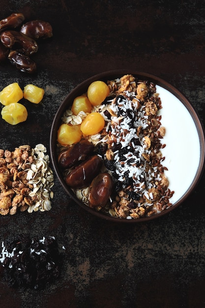 Tigela de café da manhã com iogurte grego, aveia, granola e frutas secas.