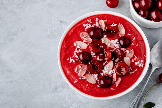 Tigela de café da manhã saudável Batido de cereja vermelha com flocos de amêndoa de frutas frescas e chips de coco