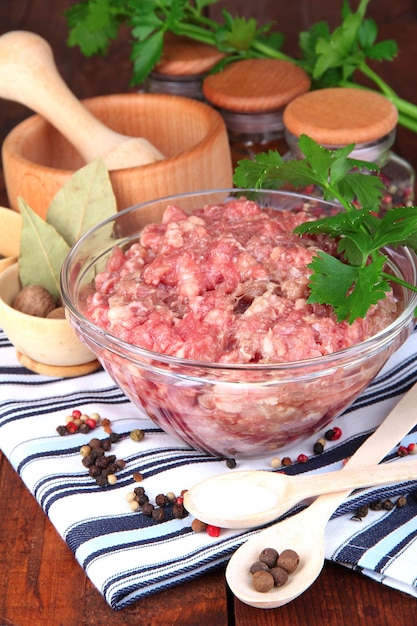 Tigela de carne moída crua com especiarias na mesa de madeira