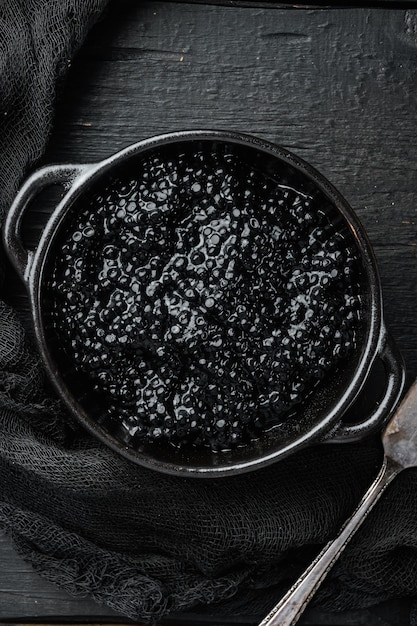 Foto tigela de caviar preto, na mesa de madeira preta, vista de cima plana lay