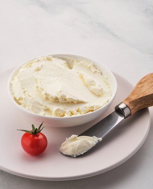 Tigela de cream cheese, molho de mergulho em fundo branco no café da manhã.