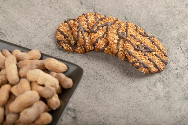 Tigela de deliciosos biscoitos com amendoim com casca orgânica na pedra.