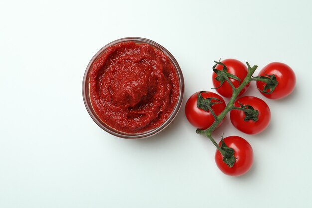 Tigela de extrato de tomate e tomate no fundo branco