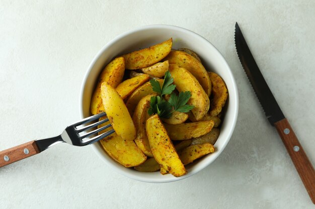 Tigela de fatias de batata e talheres em textura branca