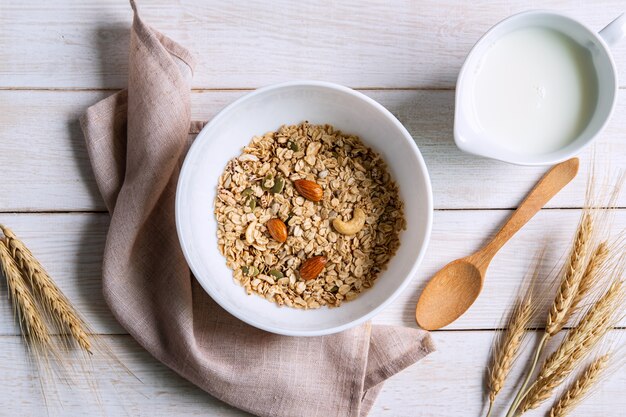 Tigela de granola amêndoa e grãos na mesa de madeira branca, café da manhã saudável