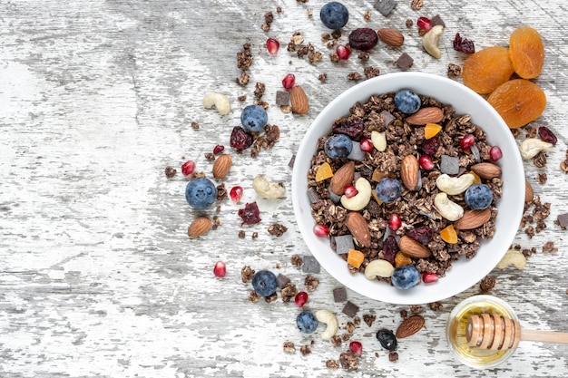 Tigela de granola de aveia de chocolate ou muesli com nozes, frutas, frutos secos e mel