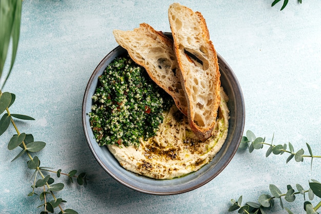 Tigela de homus com salada tabule e torradas