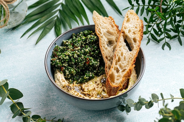 Tigela de homus com salada tabule e torradas