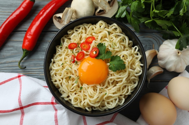 Tigela de macarrão cozido e ingredientes em madeira