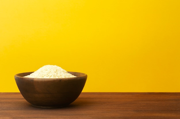 Tigela de madeira com arroz em um fundo de cor amarela. prato de madeira com arroz basmati indiano asiático na mesa