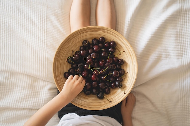 Tigela de madeira com frutas frescas e suculentas Cerejas nas mãos Fazenda de produtos ecológicos orgânicos Não OGM Cerejas vermelhas frescas