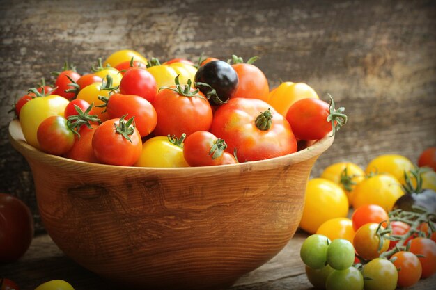 Tigela de madeira com tomates de herança amadurecidos de videira fresca do mercado de agricultores