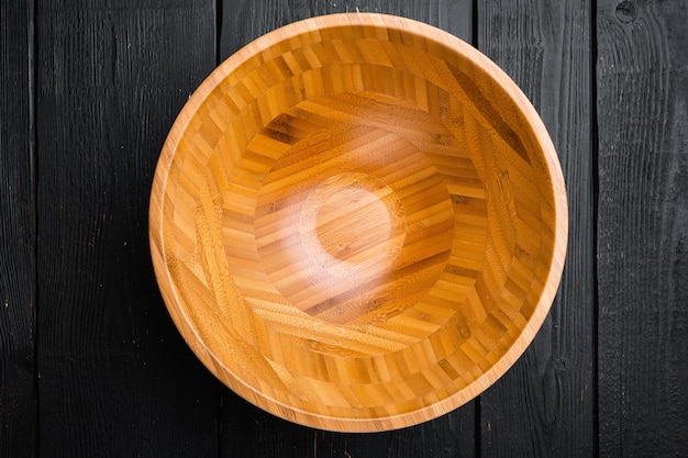 Tigela de madeira vazia definida com espaço de cópia para texto ou comida, vista superior plana leigos, no fundo preto da mesa de madeira