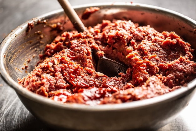 Tigela de metal cheia de carne de boi preparada na hora para tártaro de bife com colher costurada.