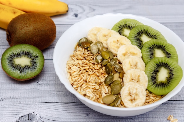 Tigela de mingau de aveia com sementes de banana, kiwi e abóbora. comida saudável no café da manhã.