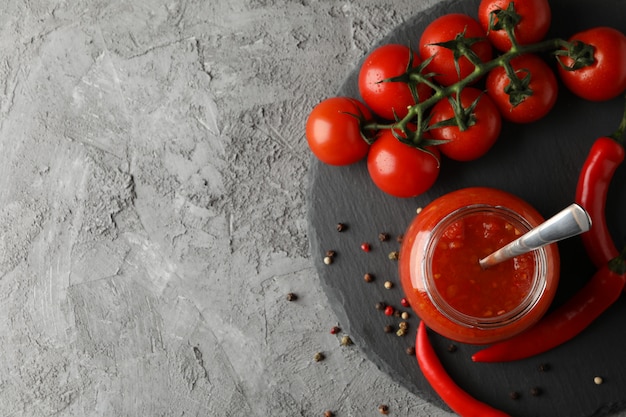 Tigela de molho de pimenta, ingredientes em fundo cinza, espaço para texto. Vista do topo