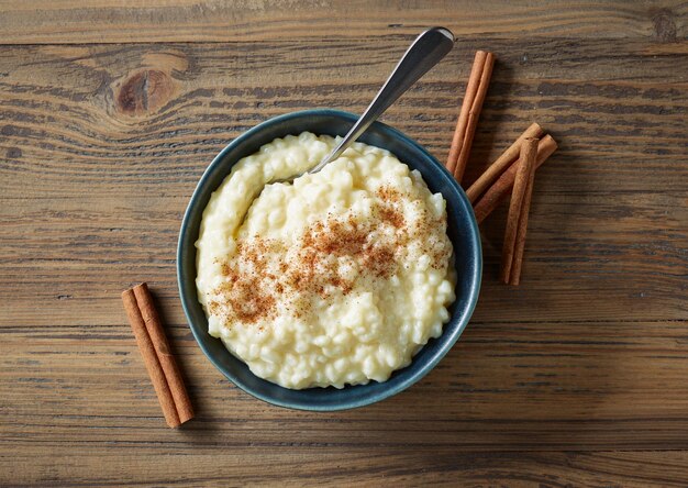 tigela de pudim de leite de arroz sem glúten com canela na mesa de cozinha de madeira, vista superior