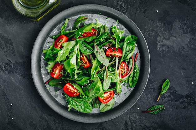 Tigela de salada de alface verde fresca com microverde de tomate e sementes de gergelim em fundo escuro Vista superior de comida saudável