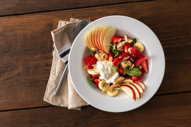 Tigela de salada de frutas em uma vista de mesa de madeira. comida saudável de verão