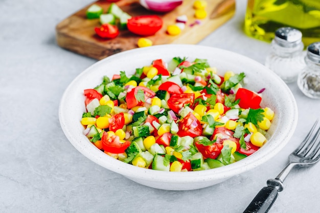 Foto tigela de salada de milho doce de verão fresco com tomates pepinos cebolas vermelhas e salsa