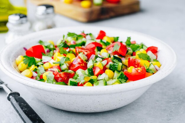 Tigela de salada de milho doce de verão fresco com tomates pepinos cebolas vermelhas e salsa