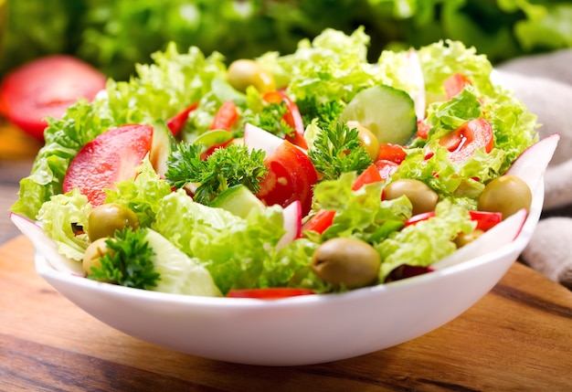 Tigela de salada fresca com legumes e verduras na mesa de madeira