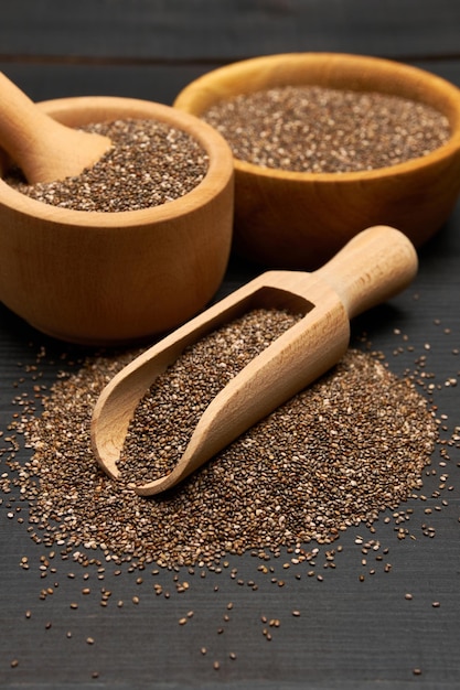 Tigela de sementes orgânicas naturais de chia e closeup de colher de madeira em um fundo de madeira ou mesa